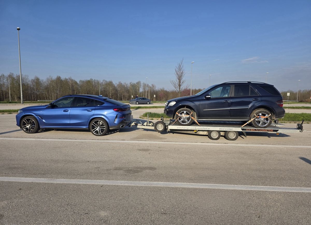 SUV zieht Autotransportanhänger mit geladenem Geländewagen
